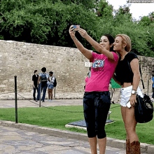 two women are taking a selfie in front of a stone wall and one of them is wearing a shirt that says cowboys