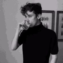 a man in a black shirt is drinking from a glass .