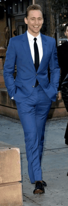 a man in a blue suit and tie is walking down the street