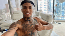 a shirtless man with a tattoo on his chest is giving a thumbs up