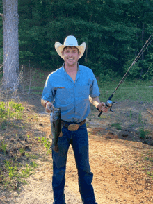 a man in a cowboy hat is holding a fish and fishing rod