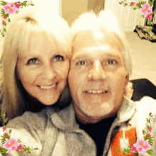 a man and a woman are posing for a picture with pink flowers surrounding them