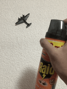 a person is spraying a bottle of raid on a white wall