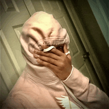 a person wearing a pink hoodie is covering their face