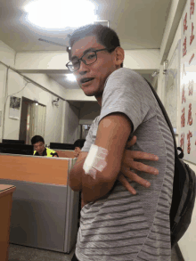 a man with a bandage on his arm stands in an office