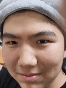 a close up of a young man 's face wearing a grey hat