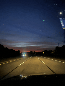 a car is driving down a highway at night with a sign on the windshield that says ' 1000 '