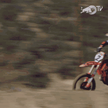 a blurred image of a person riding a dirt bike with a red bull tv logo in the background