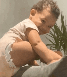 a baby in a diaper is smiling while sitting on a bed .