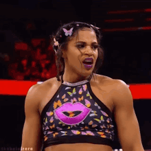 a female wrestler is wearing a colorful top with a pink lip and butterflies on it .