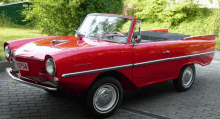 a red car with the license plate 0754 is parked on a brick driveway