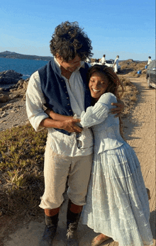 a man and a woman are hugging each other on a dirt road