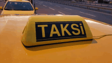 a yellow taxi has the word taksi on the top of it