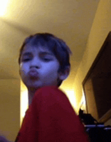 a young boy in a red shirt making a funny face