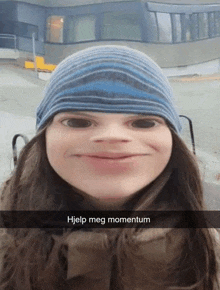 a woman wearing a blue beanie is making a funny face with help meg momentum written below her