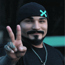 a man with a beard wearing a black beanie with a green x on it