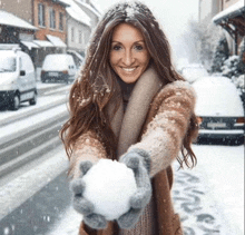 a woman is holding a snowball in her hands