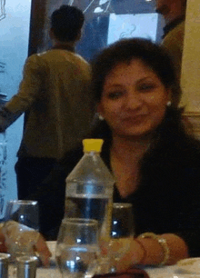 a woman is sitting at a table with a bottle of water in front of her .