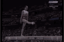 a gymnast is doing a trick on a balance beam that says longines