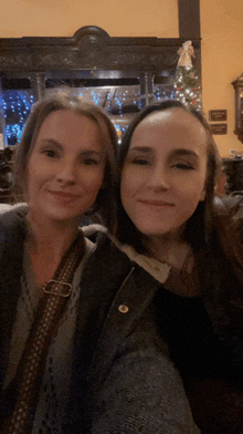 two women posing for a picture in front of a fireplace