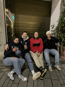 a group of people sitting on a sidewalk with one wearing a shirt that says ' ck ' on it