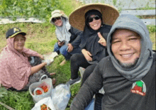 a group of people are sitting in the grass and one of them is wearing a black shirt with the word tomato on the front