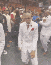 a man in a white suit and red tie is dancing