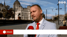 a man in a suit and tie is being interviewed in front of a building with the word hirado on the bottom