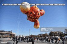 a balloon in the shape of a monster is flying in the air during the thanksgiving day parade .