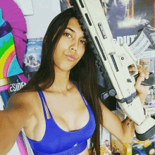 a woman in a blue tank top is holding a white gun