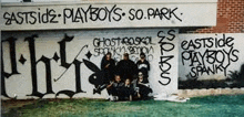 a group of people standing in front of a graffiti covered wall .