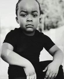 a black and white photo of a young boy in a black t-shirt