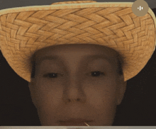 a close up of a person wearing a straw hat with a small circle in the corner