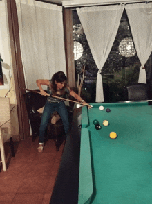 a woman holds a pool cue on a pool table with balls on it