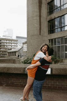 a man is holding a woman in his arms in front of a building that says ' srb ' on it