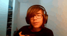 a young man wearing headphones and glasses looks at the camera