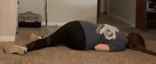 a woman in a blue shirt is laying on the floor in a living room .