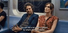 a man and a woman are sitting on a subway car with headphones on