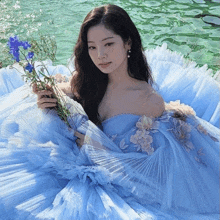 a woman in a blue dress holds flowers in her hand