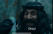 a man with a beard is holding a can that says " okay "