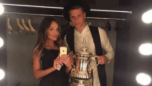 a man and a woman taking a picture of themselves holding a trophy