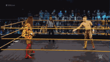 a wrestler in a gold outfit is standing in the middle of a wrestling ring