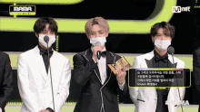 a group of men wearing face masks are standing in front of microphones and a mnet logo