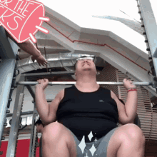 a man in a black tank top is lifting a barbell in a gym with a sign that says the basics