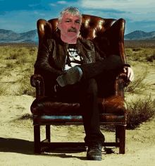 a man with a mustache is sitting in a leather chair