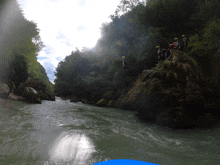 a group of people standing on a rock near a river