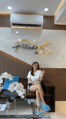 a woman sits on a couch in front of a sign that says futurent dental care