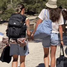 a man and a woman are walking on a beach and the man is wearing a backpack that says ' deuter ' on it