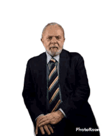 a man with a beard wearing a suit and tie is sitting with his hands folded .