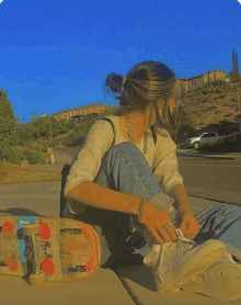 a girl sits on the sidewalk next to a skateboard that says sb on the front